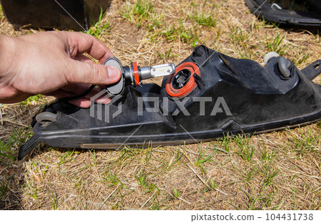 Replacing a burned out light bulb in a car headlight with an LED lamp. Close-up Replacing a burned out light bulb in a car headlight with an LED lamp. Close-up 104431738