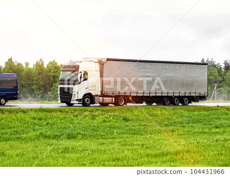 A tilt truck transports cargo on a highway in rainy weather on a slippery road. The concept of import substitution. Copy space for text A tilt truck transports cargo on a highway in rainy weather on a slippery road. The concept of import substitution. Copy space for text 104431966