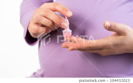 Taking a general blood test from the finger of a pregnant girl. Checking hemoglobin and red blood cells, anemia during pregnancy, close-up 104432023