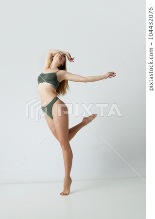 Full-length portrait of young beautiful woman with blonde hair, slim fit body posing in underwear against grey studio background 104432076