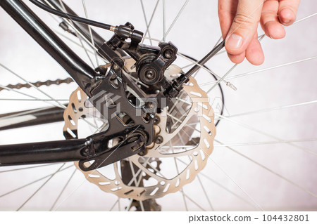 Unscrewing the bicycle brake caliper to change the brake pads and adjust the brakes. Copy space for text 104432801