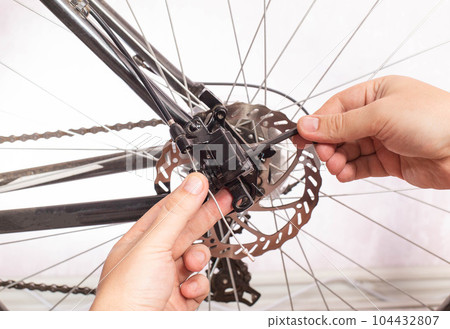 Unscrewing the brake shoe of the bicycle brake caliper with a hexagon. Replacement of brake pads, close-up 104432807