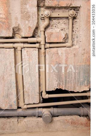 Transfer of water pipes and sewerage drain in the wall. Bathroom plumbing installation, background. Replacement of iron pipes with polypropylene ones. Transfer of water pipes and sewerage drain in the wall. Bathroom plumbing installation, background. Replacement of iron pipes with polypropylene ones. 104433036