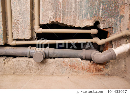 Transfer of water pipes and sewerage drain in the wall. Bathroom plumbing installation, background. Replacement of iron pipes with polypropylene ones. 104433037