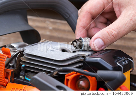 Wet spark plug in a chainsaw. Rich fuel mixture. Malfunction in the ignition system. industry Wet spark plug in a chainsaw. Rich fuel mixture. Malfunction in the ignition system. industry 104433069
