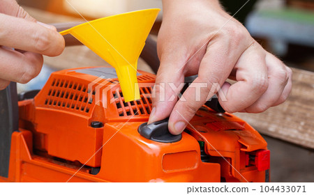 Unscrewing the cap of the fuel tank of the chainsaw for refueling a mixture of gasoline with 2-stroke oil. 104433071