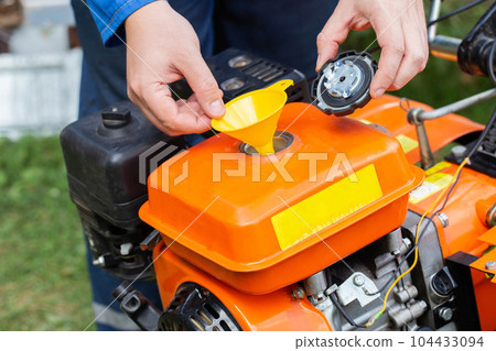 Refueling with gasoline walk-behind tractor to get started, industry. Motor cultivator 104433094