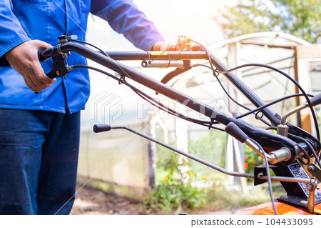 The worker adjusts the gear changes in the walk-behind tractor before running. Copy space for text, transmission 104433095