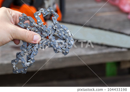 New chain for chainsaw. Setting up and replacing the chain on the chainsaw from the old to the new. Chain sharpening. Industry 104433198