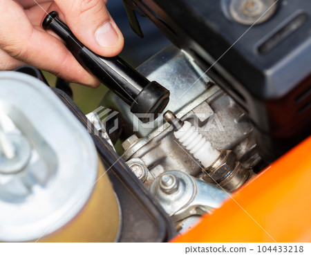 Replacing the spark plug in the motor block engine cylinder. Maintenance of the ignition system. Close-up Replacing the spark plug in the motor block engine cylinder. Maintenance of the ignition system. Close-up 104433218