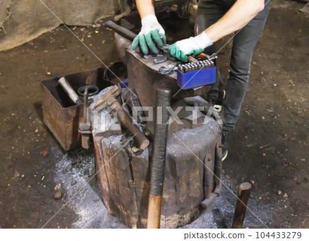 The blacksmith in the forge makes a metal part on the anvil, close-up. Industry The blacksmith in the forge makes a metal part on the anvil, close-up. Industry 104433279