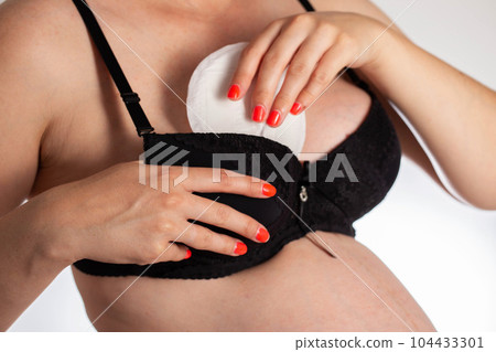 A girl in a black bra puts pads from the flow of milk in her bra. Soft, hypoallergenic breast pads. A girl in a black bra puts pads from the flow of milk in her bra. Soft, hypoallergenic breast pads. 104433301