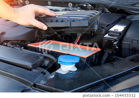 Replacing an old dirty air filter in the engine compartment of a car engine. The mechanic is servicing the car. Cleaning the air in the car engine, industry Replacing an old dirty air filter in the engine compartment of a car engine. The mechanic is servicing the car. Cleaning the air in the car engine, industry 104433332