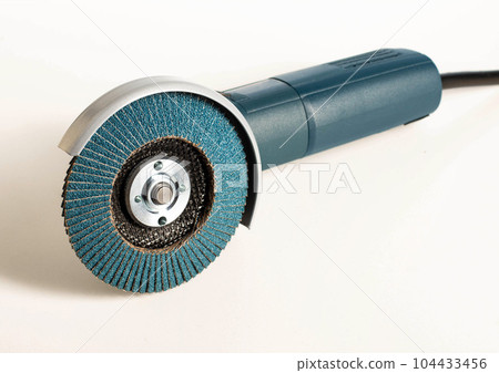 Professional angle grinder with flap wheel for processing wooden surfaces. Construction power tool. Industry, close-up Professional angle grinder with flap wheel for processing wooden surfaces. Construction power tool. Industry, close-up 104433456