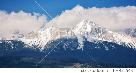 slovakia countryside in spring. snowcapped peaks beneath huge white clouds. nature background in gorgeous light slovakia countryside in spring. snowcapped peaks beneath huge white clouds. nature background in gorgeous light 104433548