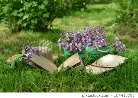 Vintage still life with open book or diary, hat and lilac flowers bouquet in the garden. Summer and spring season concept 104433795
