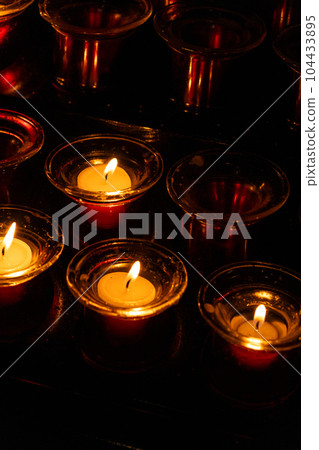 Burning candles in red candlesticks in the dark 104433895