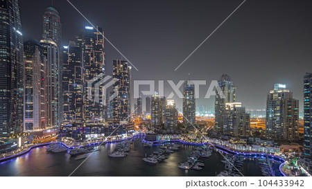 Panorama showing Dubai marina tallest skyscrapers and yachts in harbor aerial night timelapse. 104433942