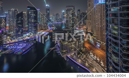 Aerial view to Dubai marina skyscrapers around canal with floating boats night timelapse 104434004