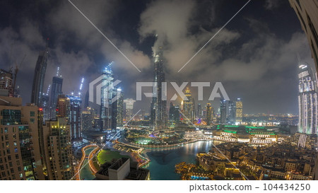 Skyscrapers rising above Dubai downtown night timelapse surrounded by modern buildings aerial top view Skyscrapers rising above Dubai downtown night timelapse surrounded by modern buildings aerial top view 104434250