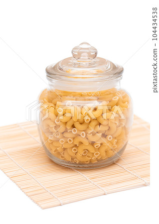 Uncooked Chifferi Rigati Pasta in Glass Jar on Bamboo Mat 104434538