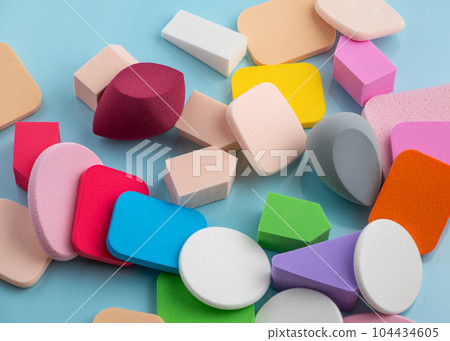 Heap of colorful cosmetic sponges on blue background. Top view Heap of colorful cosmetic sponges on blue background. Top view 104434605