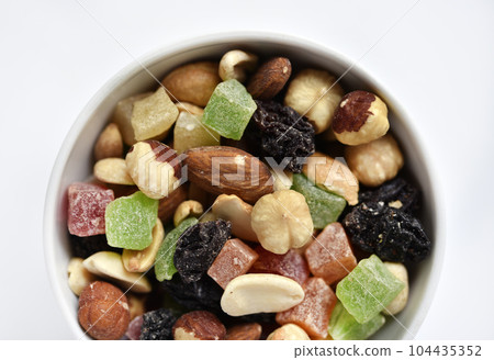 Nut mixture in a cup. A delicious snack of nuts and dried fruits. 104435352