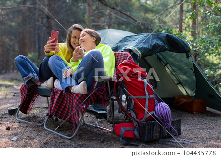 Mom and daughter during an online video call in a forest camp. Mom and daughter during an online video call in a forest camp. 104435778