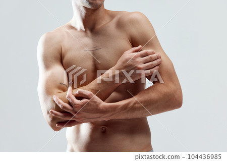 Cropped image of muscular, attractive, relief male body, breast, hands against grey studio background. SHirtless model Cropped image of muscular, attractive, relief male body, breast, hands against grey studio background. SHirtless model 104436985