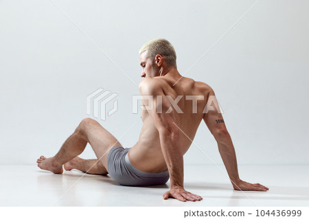 Young handsome man with muscular, relief, fit, strong body posing on floor in underwear against grey studio background 104436999