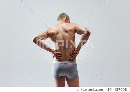 Rear view image of young man with muscular, relief, fit, strong healthy body, back, posing in underwear shirtless Rear view image of young man with muscular, relief, fit, strong healthy body, back, posing in underwear shirtless 104437008