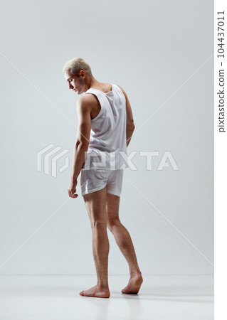 Comfort look. Full-length image of young handsome man with muscular body posing in underwear and singlet against grey studio background Comfort look. Full-length image of young handsome man with muscular body posing in underwear and singlet against grey studio background 104437011