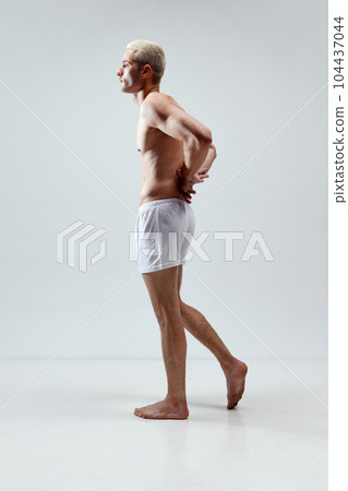 Full-length image of young, handsome, stylish man with muscular body posing in underwear against grey studio background Full-length image of young, handsome, stylish man with muscular body posing in underwear against grey studio background 104437044