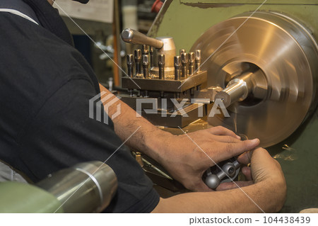 The machine operator working with lathe machine. The machine operator working with lathe machine. 104438439