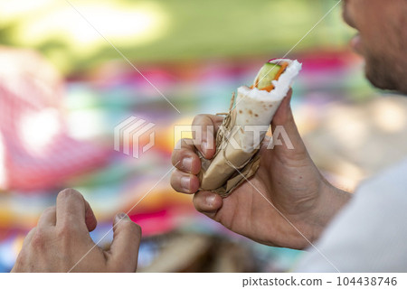man is holding a burrito in his hand 104438746