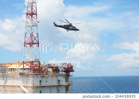 Helicopter Landing Officer communicating with pilot and copilot for service on ground and support as the pilot required. The helicopter landing on the deck in oil and gas platform 104438935