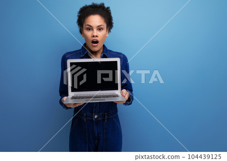 young successful woman with dark skin and black curly hair dressed in a blue denim suit demonstrates 104439125