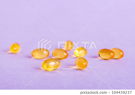 Heap of yellov pills on colored background. Tablets scattered on a table. Pile of red soft gelatin capsule. Vitamins and dietary supplements concept Heap of yellov pills on colored background. Tablets scattered on a table. Pile of red soft gelatin capsule. Vitamins and dietary supplements concept 104439237