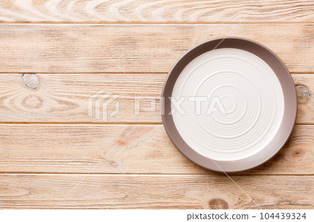 Top view of empty light plate on wooden background. Empty space for your design Top view of empty light plate on wooden background. Empty space for your design 104439324