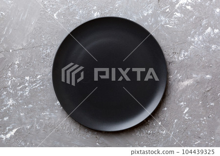 Top view of black plate on cement background. Empty space for your design 104439325
