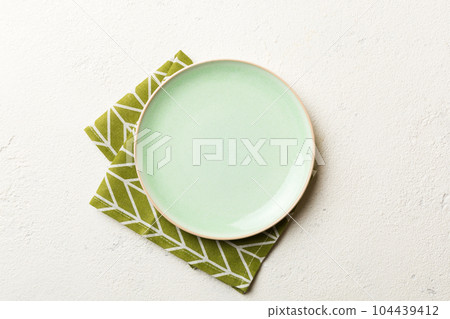 Top view on colored background empty round green plate on tablecloth for food. Empty dish on napkin with space for your design 104439412