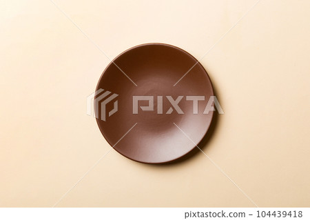 Top view of isolated of colored background empty round brown plate for food. Empty dish with space for your design Top view of isolated of colored background empty round brown plate for food. Empty dish with space for your design 104439418