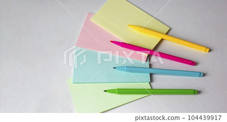 Colored felt-tip pens and multi-colored stickers on a light background Colored felt-tip pens and multi-colored stickers on a light background 104439917