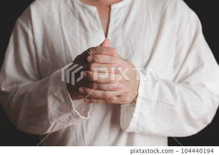 An adult whose hand is prayed on the dark background.Respect for belief in religion and God. front view. peace concept. 104440194