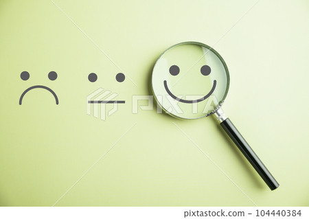 Magnifying glass reveals smiley face, finding happiness amid sadness. Customer satisfaction and evaluation after service survey. Magnification, satisfaction, reputation, corporate, customer 104440384