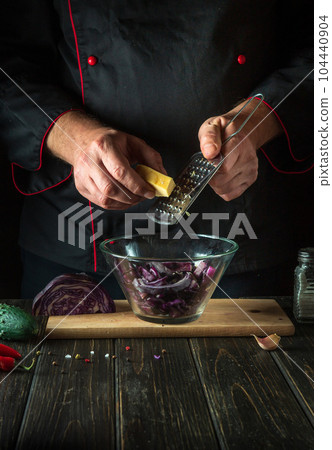 The cook adds cheese to a fresh red cabbage salad in a restaurant kitchen. Cooking healthy or vegetarian food. 104440904