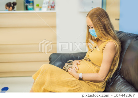 young woman in the waiting room interview sitting on sofa in corridor of dentist office or reception modern medical center while doctor's appointment. using mobile phone fills information or resumes 104442367