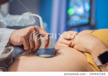 In the Hospital, Close-up Shot of the Doctor does Ultrasound Sonogram Procedure to a Pregnant Woman. Obstetrician Moving Transducer on the Belly of the Future Mother In the Hospital, Close-up Shot of the Doctor does Ultrasound Sonogram Procedure to a Pregnant Woman. Obstetrician Moving Transducer on the Belly of the Future Mother 104442368