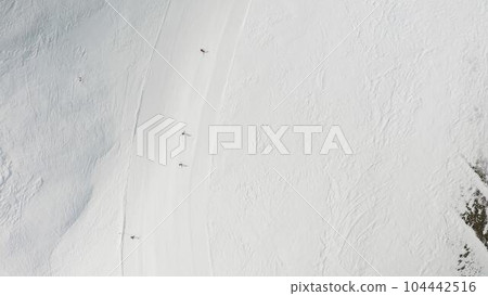People snowboarding skiing at ski resort. Skiers, snowboarders riding snowy mountain slope. Outdoor winter sport. Aerial, top view 104442516