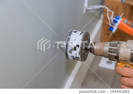 Drilling drywall for installation of electrical wires in wall is one tasks 104442662